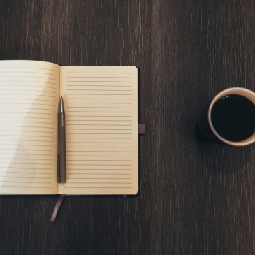 Open blank journal on a table with a cup of coffe