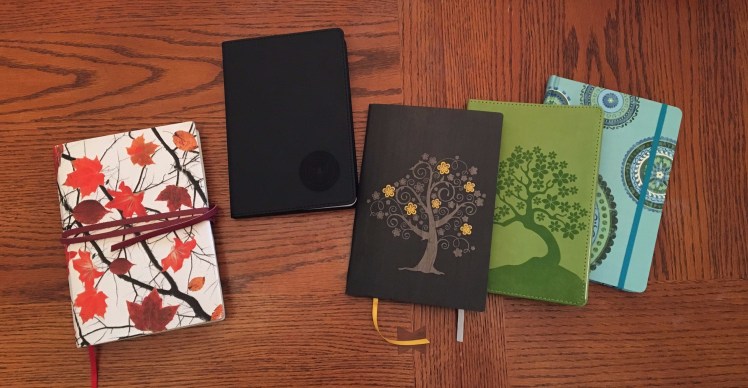 five journals on a wooden table